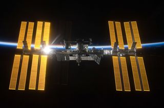 A photo of the International Space Station with a backdrop of space and the thin blue line of Earth's atmosphere.